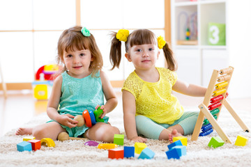 Poster - Children playing together. Toddler kid and baby play with blocks. Educational toys for preschool and kindergarten child. Little girls build toys at home or daycare.