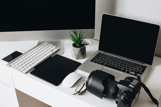 Photographer work desk with camera, laptop, tablet and computer