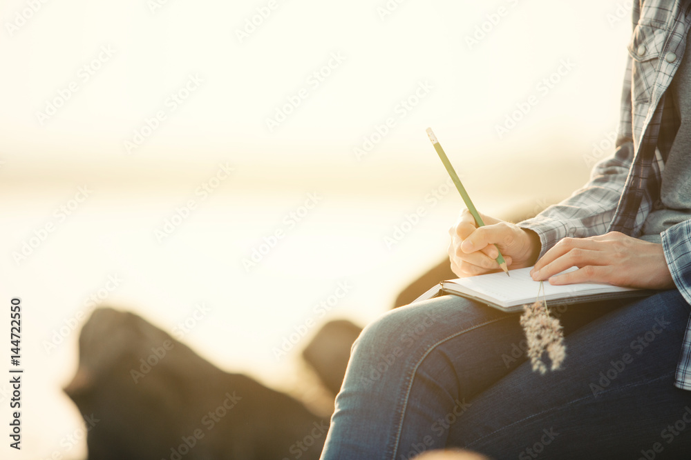  woman writing on a journal about her hiking trip,flare light - obrazy, fototapety, plakaty 