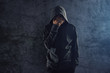 Depressed hooded person leaning on wall and crying