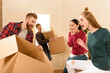 © LIGHTFIELD STUDIOS - cheerful friends holding cardboard boxes at new home