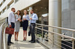 © pressmaster - Group of young successful business people talking, discussing work outside modern office building