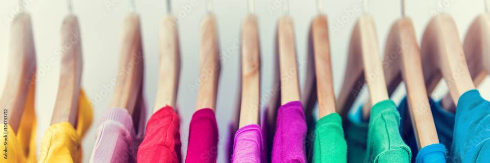 Banner horizontal crop for text background of clothing rack. Clothes for women hanging on hangers in home closet or shopping mall for store sale concept. Colorful selection of t-shirts. - obrazy, fototapety, plakaty 