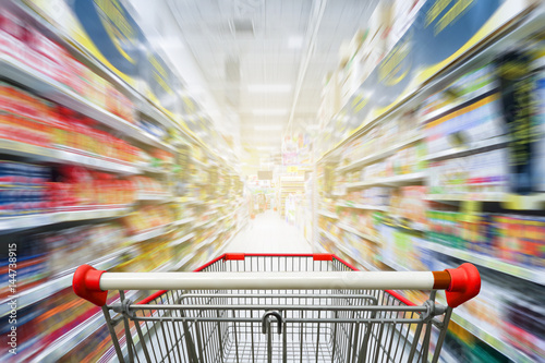 Fotografía Supermarket aisle with empty red shopping cart