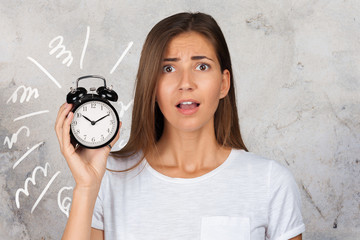 Girl holding alarm clock in hand