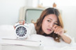 Young woman sleeping  on white bed and alarm clock in bedroom at home.