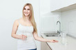© Saksoni - Beautiful young woman holds a glass with water on kitchen