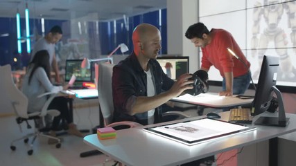  Young creative computer game designer working with colleagues in dark office.