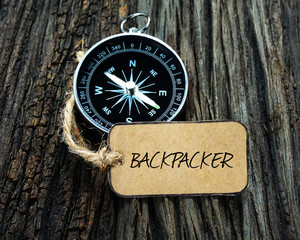 Wall Mural - Compass and paper tag written with BACKPACKER on wooden background.
