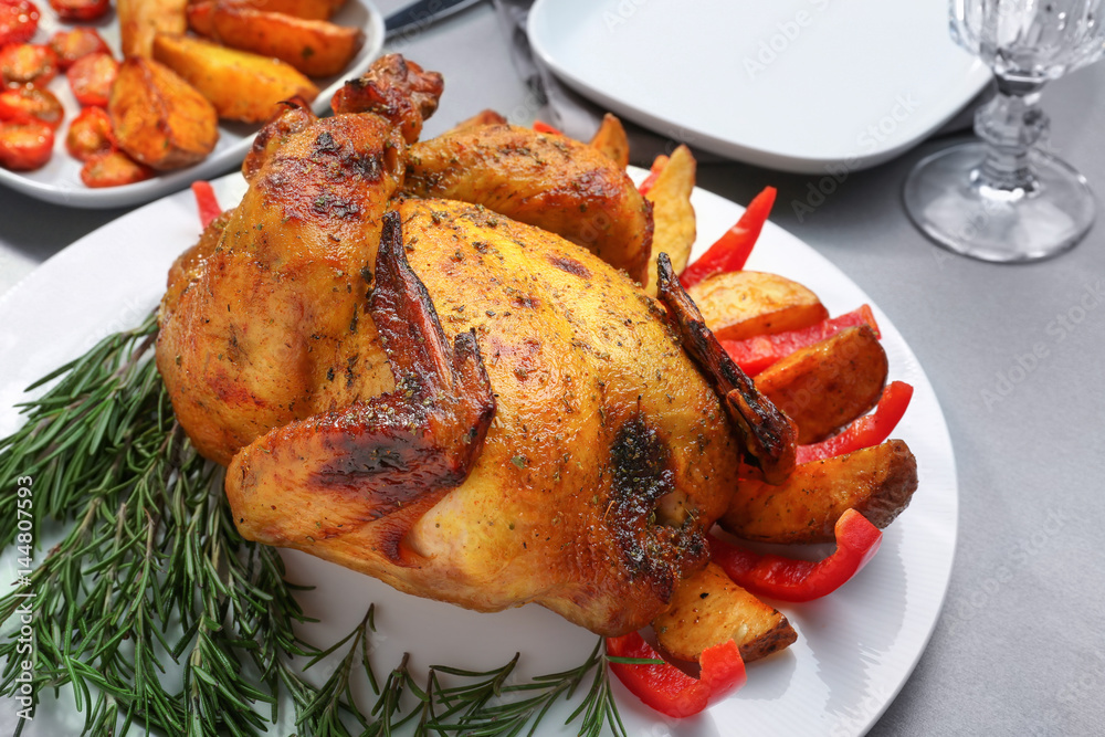 Plate with roasted beer can chicken on gray table