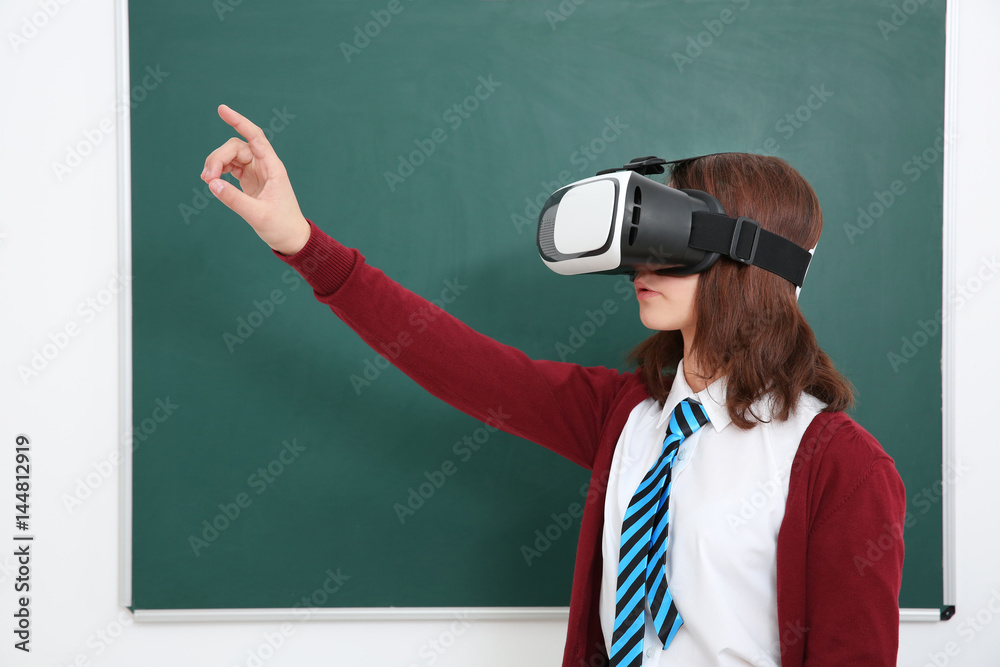 Schoolgirl with virtual reality glasses in classroom