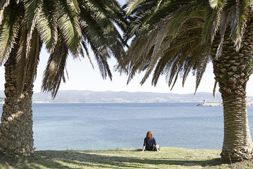 Redhead woman sitting and looking at the sea