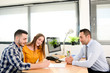 © W PRODUCTION - happy young couple in office with businessman on business buying agreement contract signature