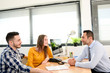 © W PRODUCTION - happy young couple in office with businessman on business buying agreement contract signature