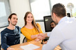 © W PRODUCTION - hand shaking and buying agreement contract signature between a young couple and a professional finance business man in office
