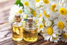 Essential Oil In Glass Bottle With Fresh Chamomile Flowers, Beauty Treatment. Spa Concept. Selective Focus. Fragrant Oil Of Chamomile Flowers, Macro On Wooden Table Horizontal. 