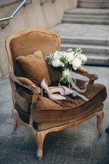 Wall Mural - beautiful beige bridesmaid shoes with white bouquet lying on a brown easy chair