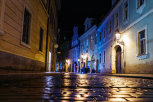 Illuminated Cobbled Street With Light Reflections On The Pavement In Old Historical City By Night In Prague