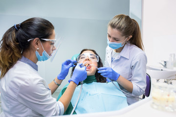 Wall Mural - Patient with two dental doctors. Procedure at dentist office. Therapy and treatment of teeth.