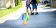 © _jure - Children learning to roller skate on the road with cones.