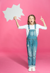 Wall Mural - Adorable little girl holding blank speech bubble and pointing up with finger