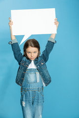 Wall Mural - Upset little girl holding blank speech bubble and looking at camera