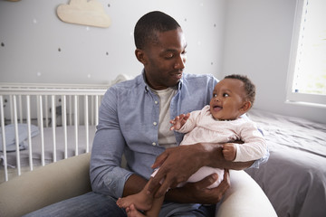 Wall Mural - Father Holding Baby Daughter In Nursery