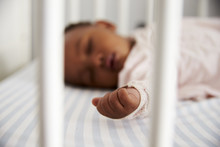 Close Up Of Baby Girl Sleeping In Nursery Cot