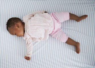 overhead shot of baby girl sleeping in nursery cot