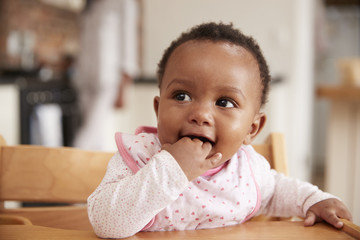 Cute Baby Girl Wearing Bib Sitting In High Chair