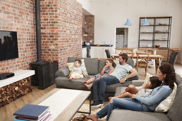 Wall Mural - Family Sit On Sofa In Open Plan Lounge Watching Television