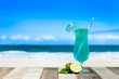 Refreshing blue cocktail on beach table..