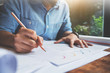 © eggeeggjiew - Close Up man hand writing on document papers with pencil. Freelance designer drawing his job.