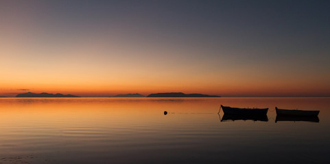 A warm sunset on a calm water, with Islands in the background