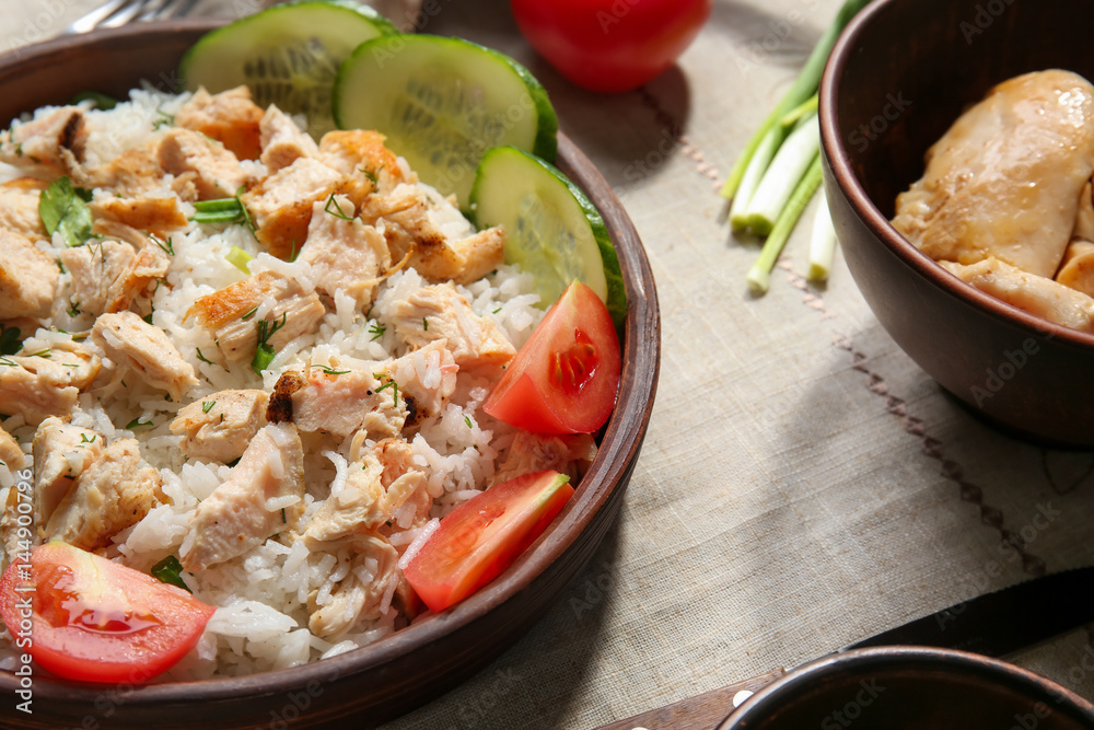 Delicious rice with chicken and vegetables in bowl on table