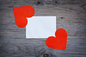 Red paper hearts Valentine's card with a clean white sheet of paper. Space for text. Wooden background texture