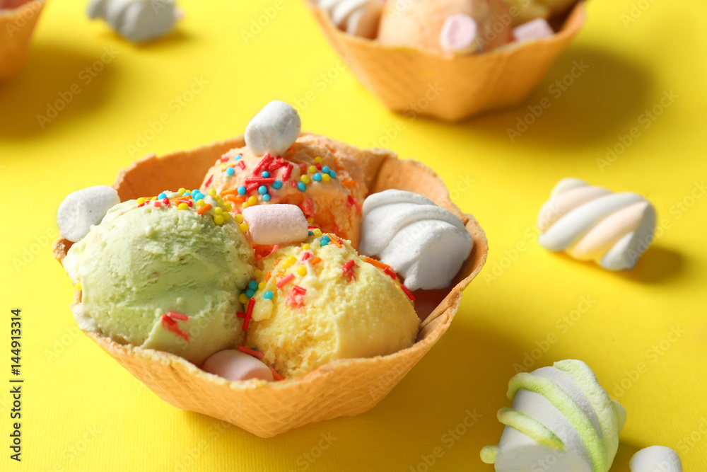 Wafer bowls with different ice-cream and marshmallows on table