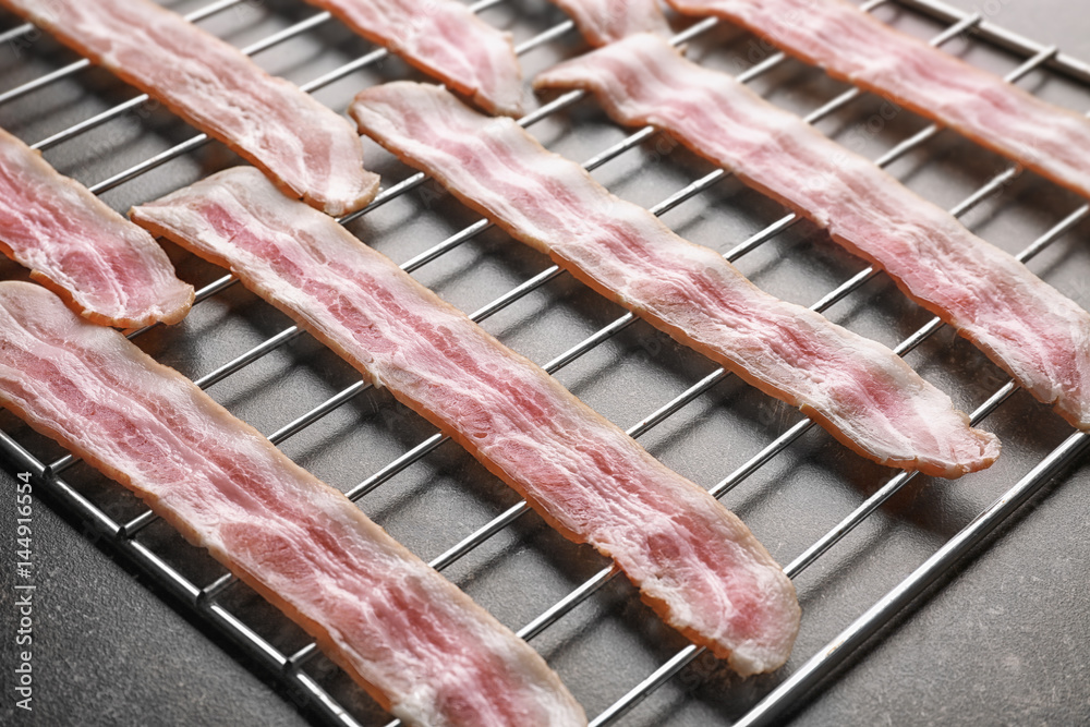 Grill with strips of bacon on table