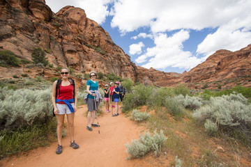 Wall Mural - Smiling group of hikers enjoying the day hiking together along a beautiful desert cliff hiking trail in Utah.