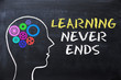 Learning never ends message  on blackboard with human head shape and gears 