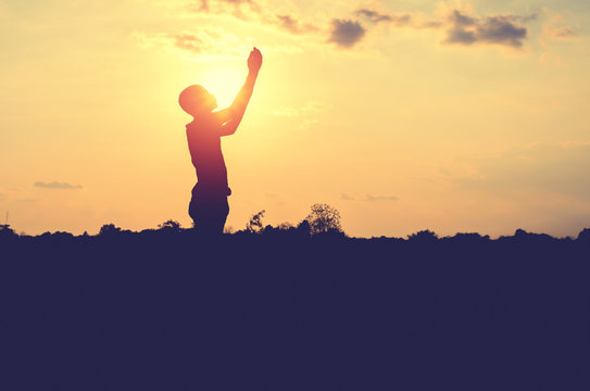 Silhouette of man pray with sunset background