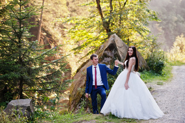  Lovely wedding couple against river with stones at Carpathian mountains.