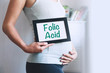 Pregnant woman holds whiteboard with text message - FOLIC ACID.