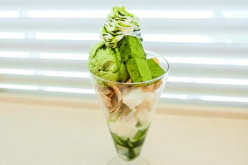 Green Tea Ice cream with Vanilla Soft Cream and Green tea chocolate garnished with Whipped cream and corn flake