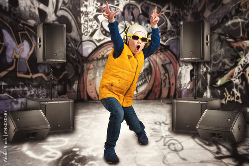 Fototapeta na wymiar Boy dancing Hip-Hop . Children's fashion.The Young Rapper.Graffiti on the walls.Cool rap DJ.