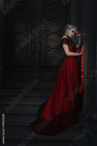 Sad woman in retro Victorian style with red ribbon in hands.