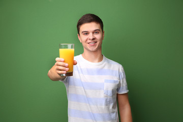 Poster - Young man drinking juice on color background