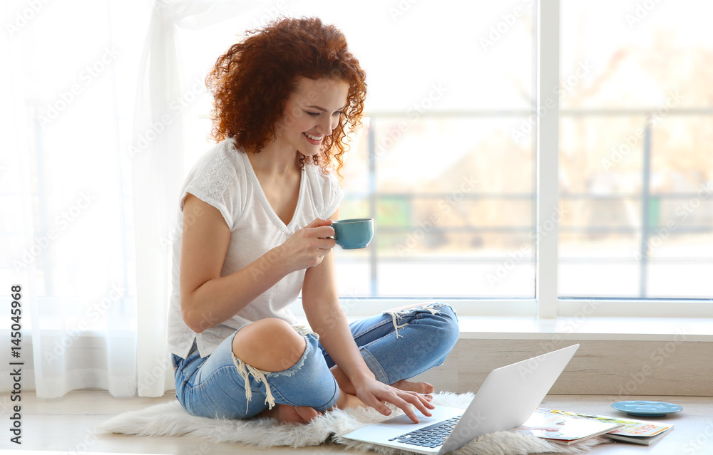 Beautiful young woman using laptop at home
