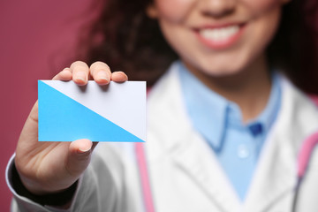 Poster - Female doctor with business card on color background, closeup