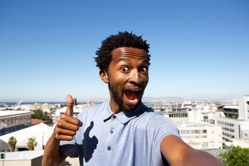 african american man standing by urban background with thumb up